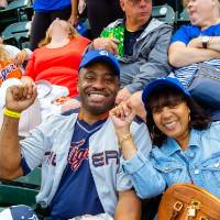 A smiling older couple holding up their fist in support of the tigers from their seats